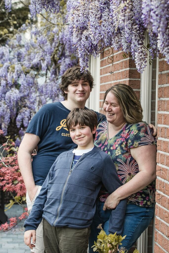Famille à l'extérieur qui sourit et est heureuse. Ce sont deux enfants avec leur maman.
