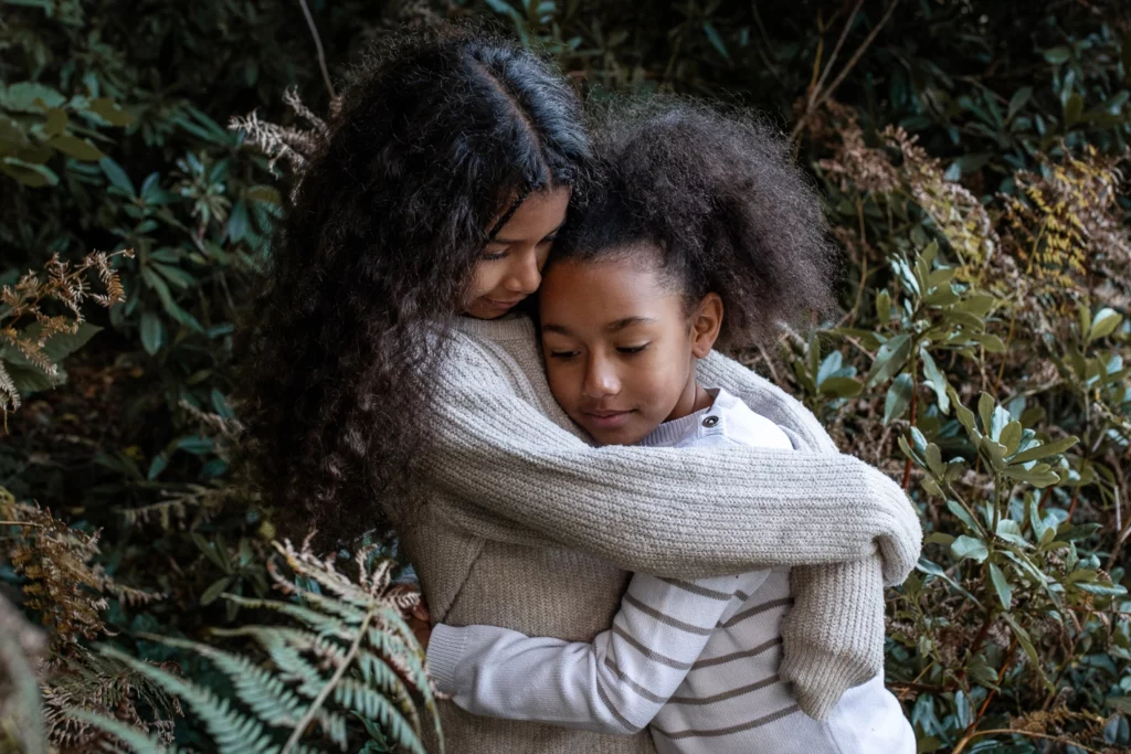Enfant qui se font un câlin devant un sapin. format lifestyle