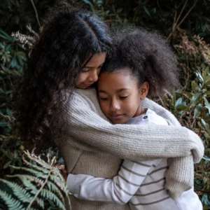 Enfant qui se font un câlin devant un sapin. format lifestyle