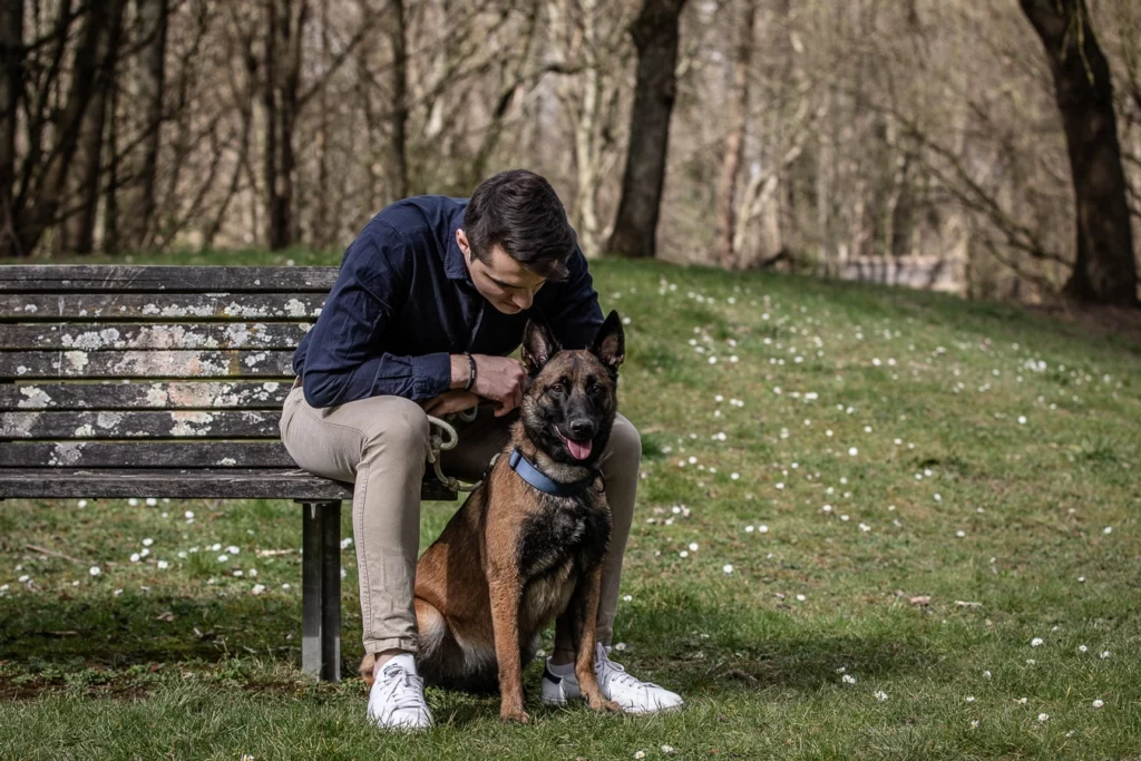 Homme avec son chien assis sur un banc dans un parc. Photo d'un animal