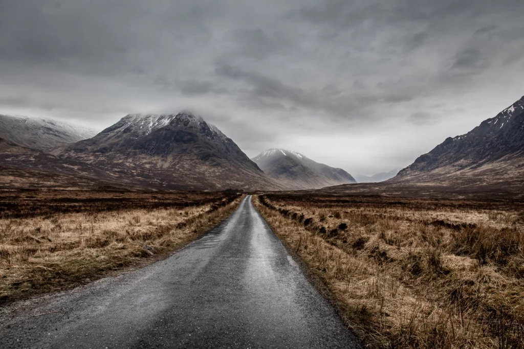 Route de Glen Etive qui passe à travers la montagne et les plaines avec le ciel nuageux.