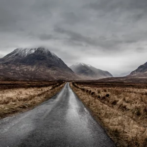 Route de Glen Etive qui passe à travers la montagne et les plaines avec le ciel nuageux.